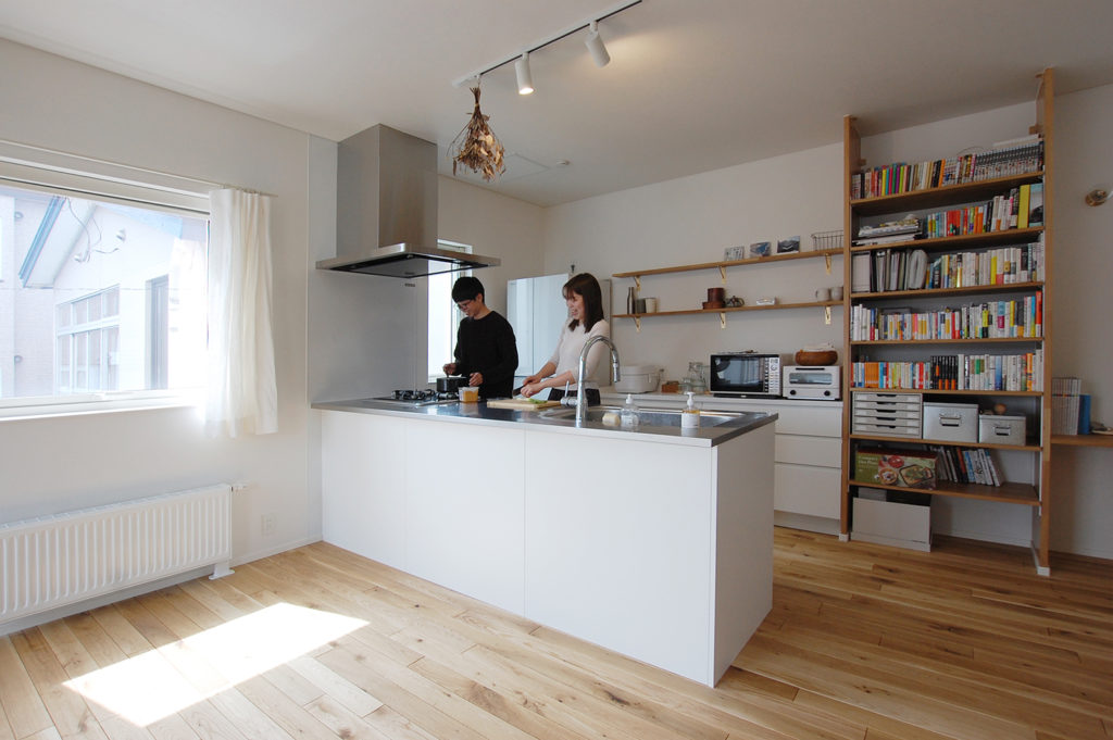白を基調としたペニンシュラキッチンと木製のオープン棚