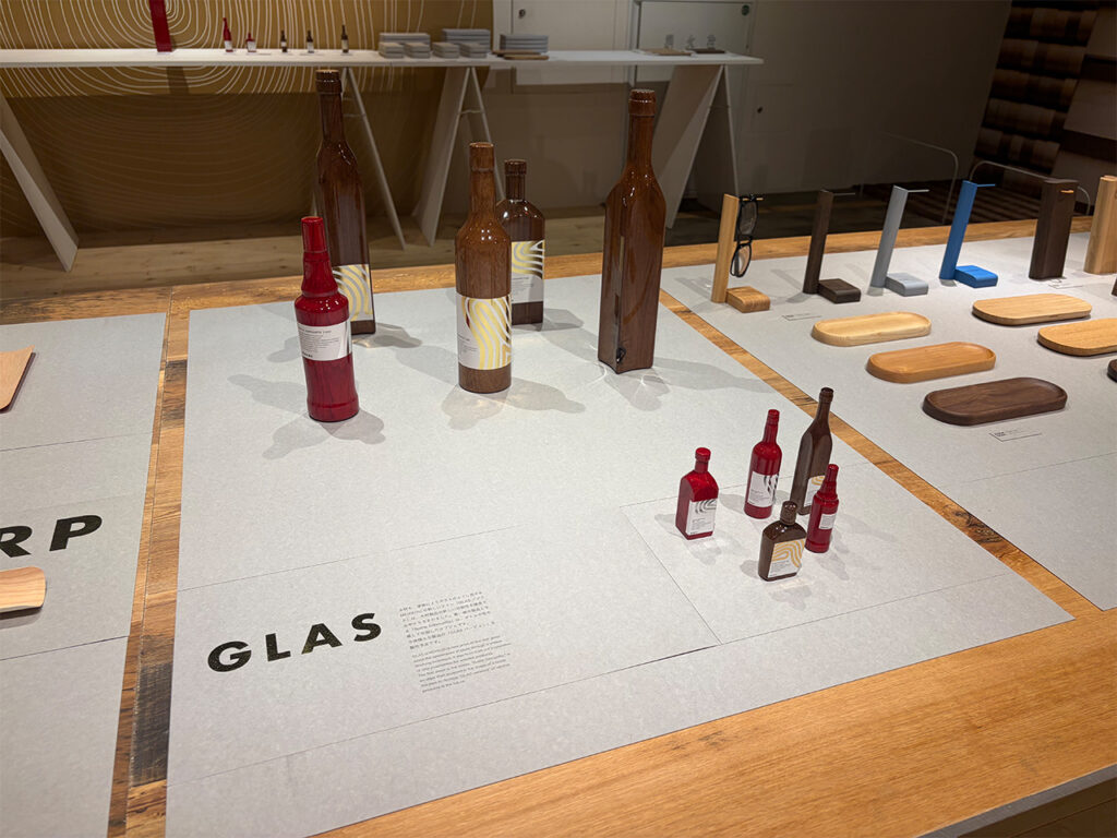 旭川デザインセンターに展示された、木材に特殊塗装を施しガラスボトルのような艶と質感を表現したMOKKOU（モッコウ）の「GLAS」シリーズ