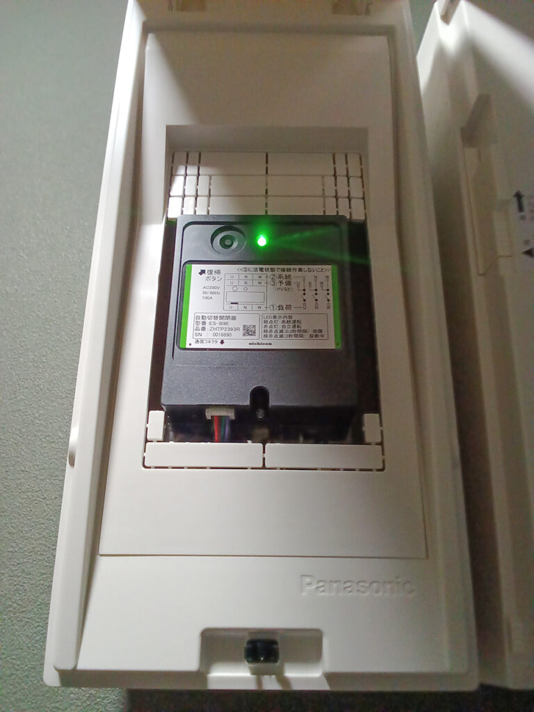 パナソニック製ケースに収納され緑色LEDが点灯している、停電時に活躍するニチコン製の自動切替開閉器