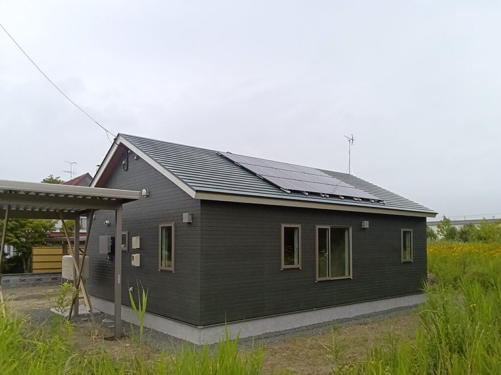 屋根に美しく太陽光パネルが搭載された、モスグリーンでモダンな外壁がおしゃれなイワクラホームの平屋の建築実例外観