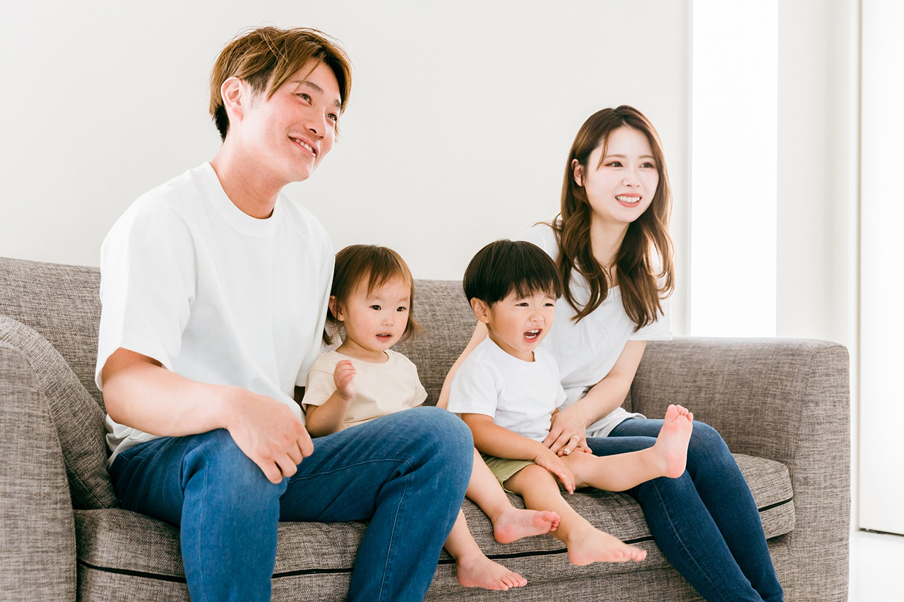 明るいリビングでソファに座り、家族でくつろぐ様子。モデルハウスでの快適な暮らしをイメージできます。