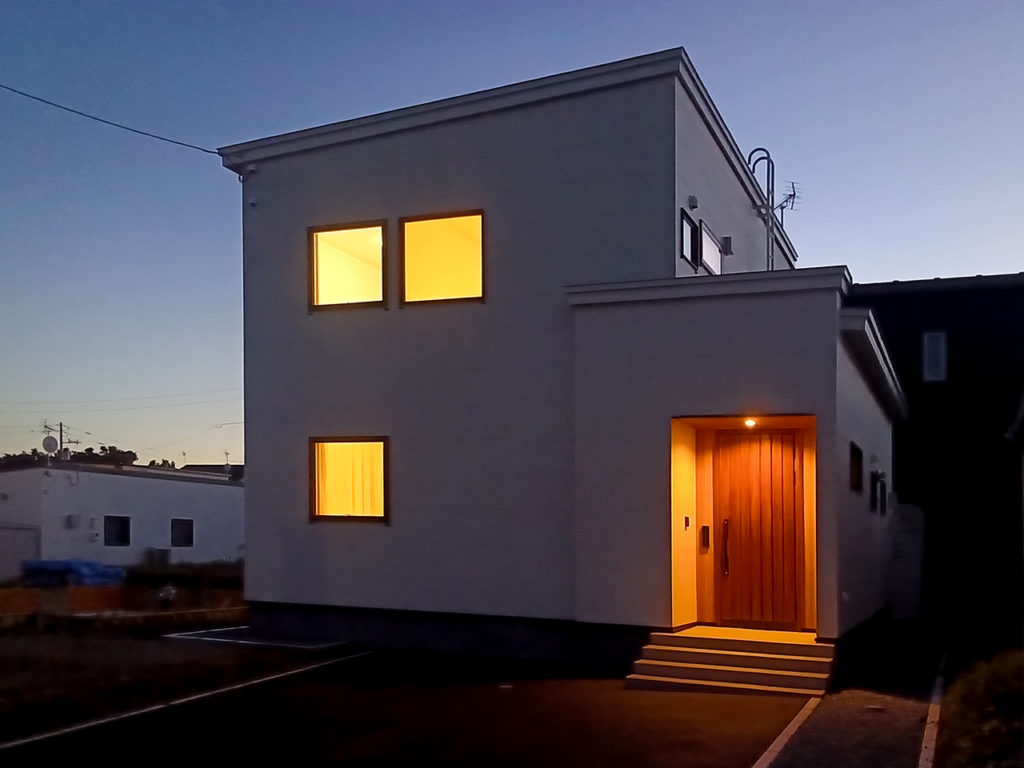 夕暮れに灯りがともる室蘭市八丁平モデルハウスの外観