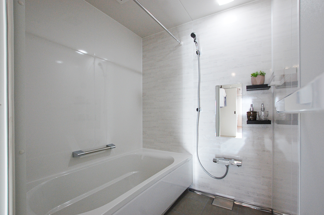 タカラスタンダード「リラクシア」のババスルーム実例。白い浴槽と、ライトグレーの重厚感のあるタイル調の壁パネルを使った清潔感あふれるバスルーム。