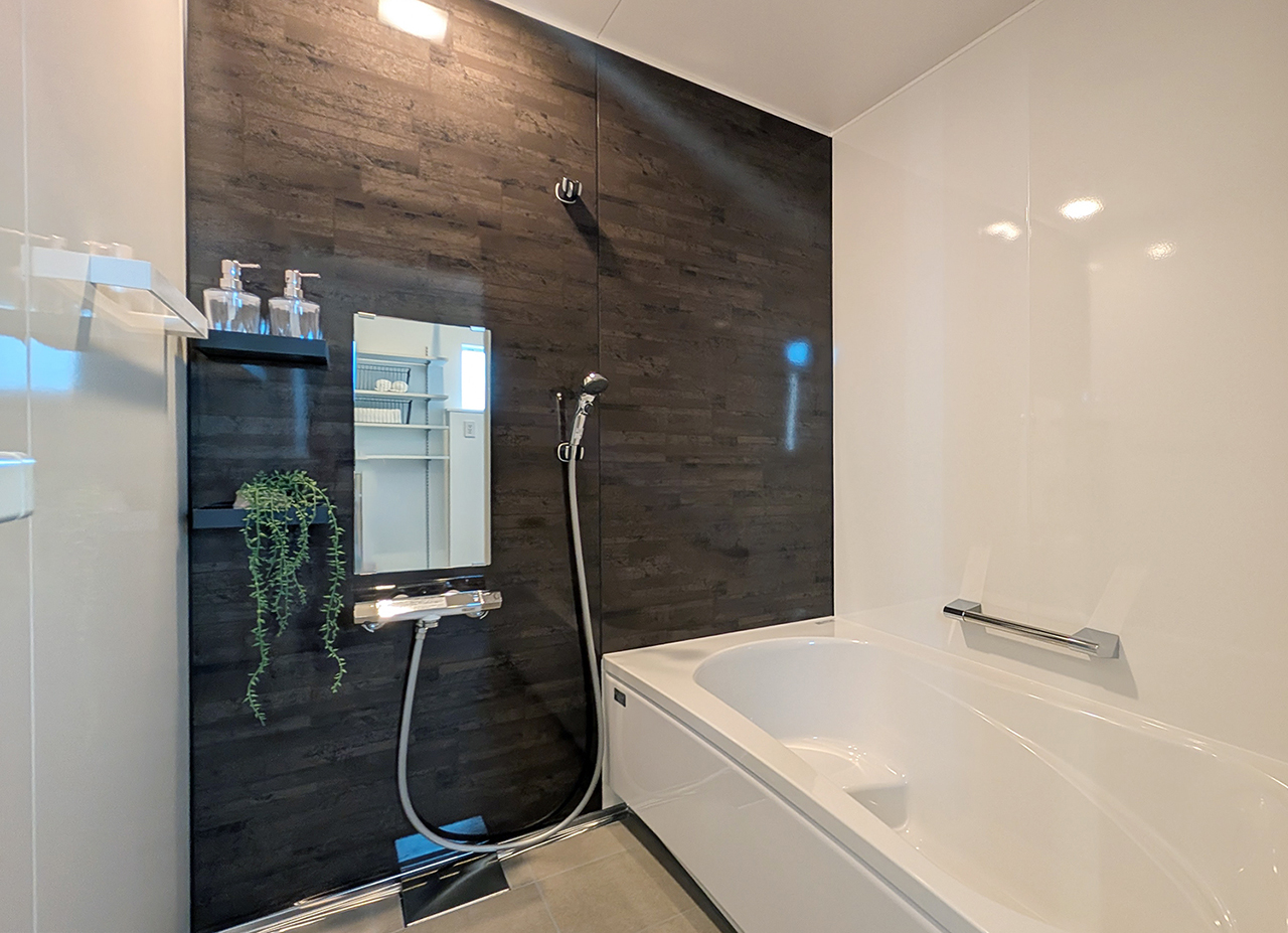 タカラスタンダード「リラクシア」のバスルーム。ダークブラウンのパネルが特徴的なバスルーム。鏡の横にはグリーンが飾られている。