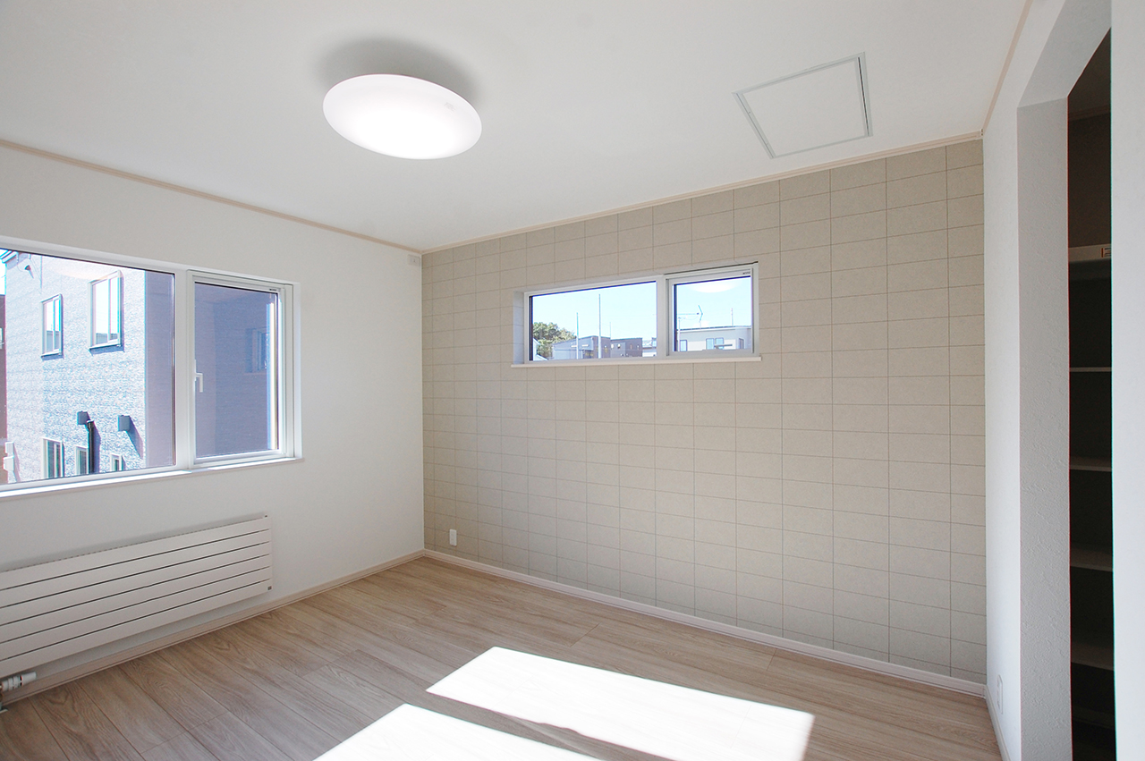 主寝室のアクセントにSP2566の大きなタイル柄クロスを採用した落ち着きのある空間