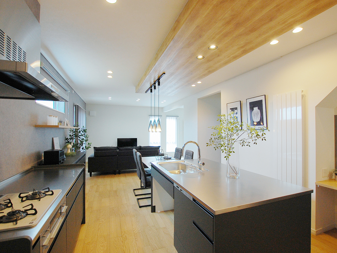 タカラスタンダードの二列型キッチン「オフェリア」の施工事例。ブラックの面材とステンレス天板、木目調の下がり天井がおしゃれなLDK。