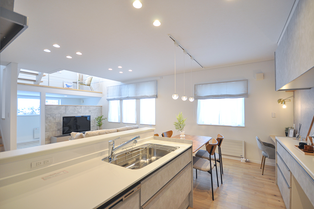 イワクラホーム施工事例:LIXILの白いシステムキッチンがある清潔感あふれるLDK。人造大理石カウンターとシンク。